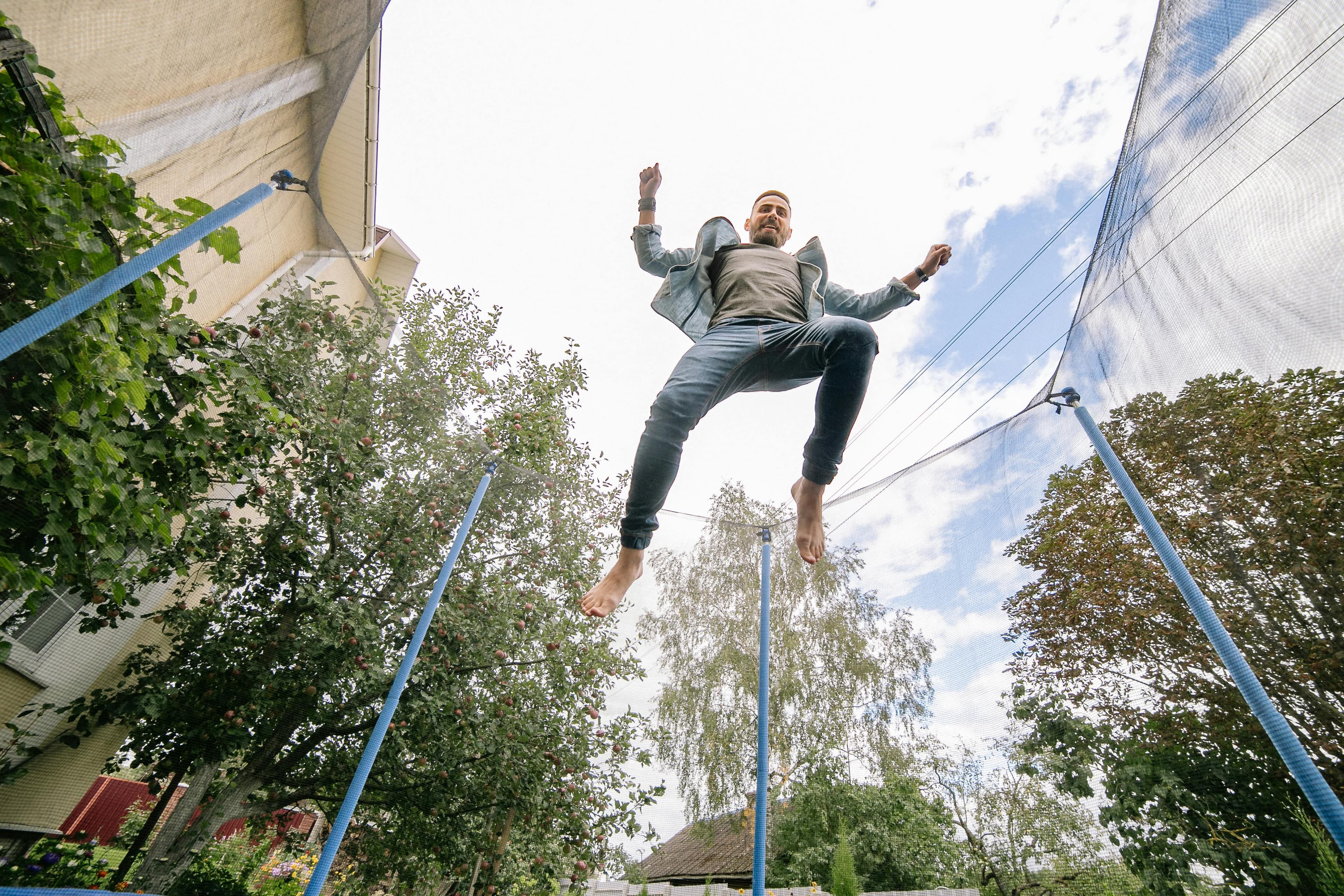 A man jumping on an outdoor trampoline.