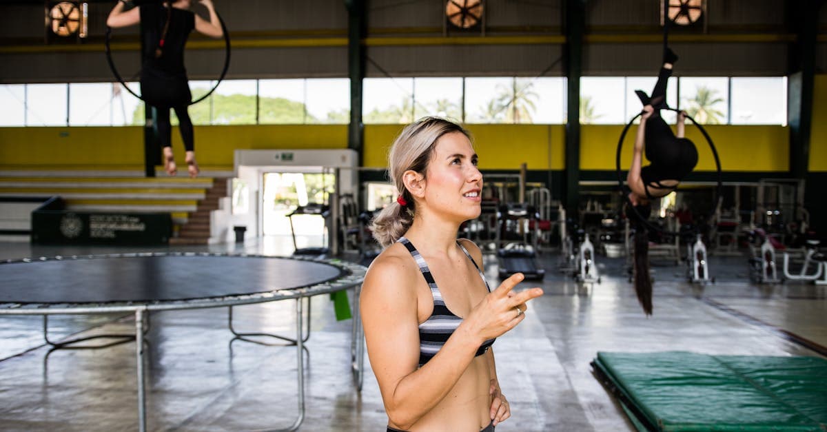 An indoor fitness setting with a coach and exercise trampolines.