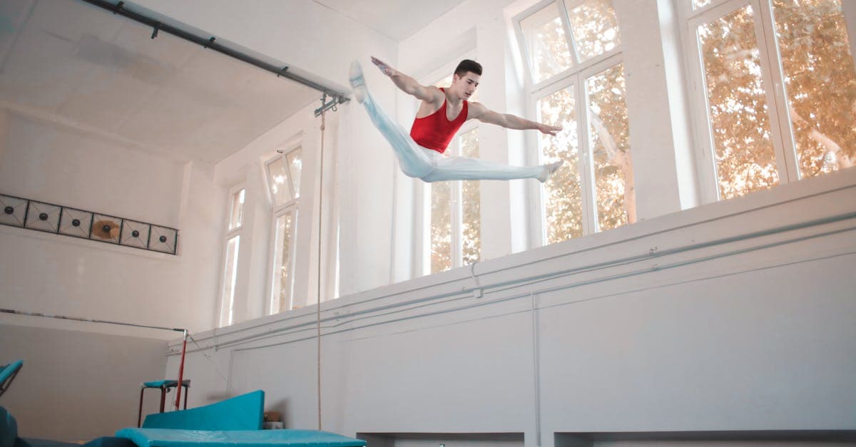 A gymnast jumping high on a trampoline in an indoor training space.